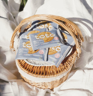 Wicker basket with Toto cookies packaging on a white fabric background